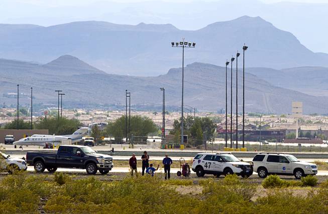 Officials are shown near the site of where a small plane is crash-landed short of the runway at the Henderson Executive Airport in Henderson Thursday, July 28, 2016. No one was injured in the accident, officials said.