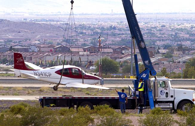 A small plane is lifted onto a flatbed after crash-landing short of the runway at the Henderson Executive Airport in Henderson Thursday, July 28, 2016. No one was injured in the accident, officials said.