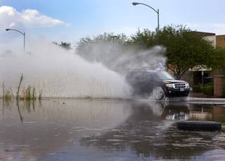 A sports utility vehicle drives through storm run-offf on Fort Apache Road following a rainstorm Sunday, July 31, 2016.