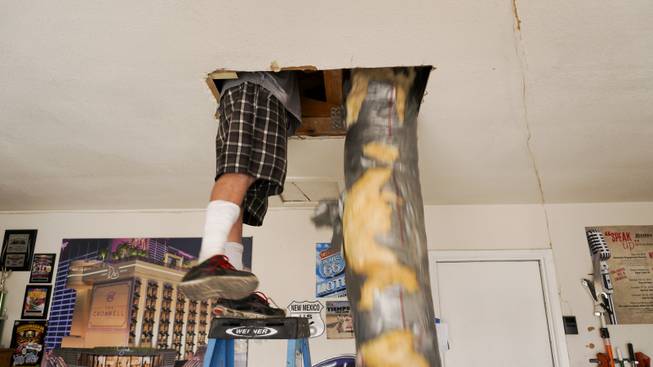 Richie Neill, employee of Ruiter Construction LLC, helps remove old A/C ventilation air ducts from the attic during a weatherization project at Allen Ford's home Thursday, Aug. 4, 2016.  HELP teams up with contractors like Ruiter Construction LLC to assist NV Energy customers in low-income households with A/C repairs and upgrades.