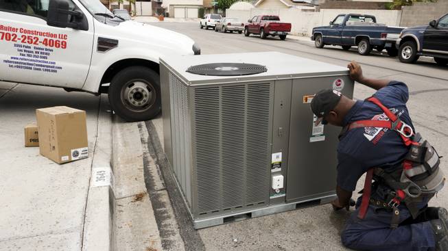 Lashon Ford, an air conditioning specialist with Ruiter Construction LLC, readies an new A/C unit for installation during a weatherization project at Allen Ford's home Thursday, Aug. 4, 2016.  HELP teams up with contractors like Ruiter Construction LLC to assist NV Energy customers in low-income households with A/C repairs and upgrades.