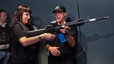 Trisha Morris prepares to fire an AR-15 with assistance from Chief Range and Safety Officer Billy Karl during a media tour of the new Top Shot facility which uses real guns to play out interactive virtual and lifelike shooting scenarios  on Friday, August 19, 2016. Morris is with 24x7 Magazine.