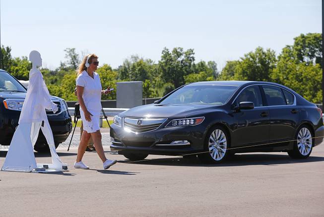 In this July 20, 2015 file photo, a pedestrian crosses in front of a vehicle as part of a demonstration at Mcity on its opening day on the University of Michigan campus in Ann Arbor, Mich. Automakers say cars that wirelessly talk to each other are finally ready for the road. The cars hold the potential to dramatically reduce traffic deaths, improve the safety of self-driving cars and someday maybe even help solve traffic jams.