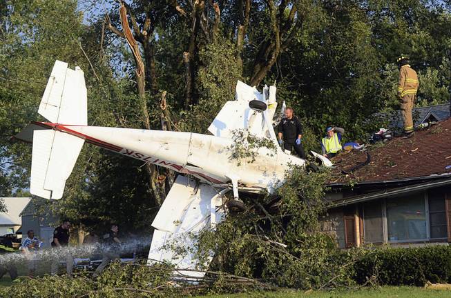 Rescue personnel help at the scene where a small plane crashed into a house a few miles north of Terre Haute, Ind., on Thursday.