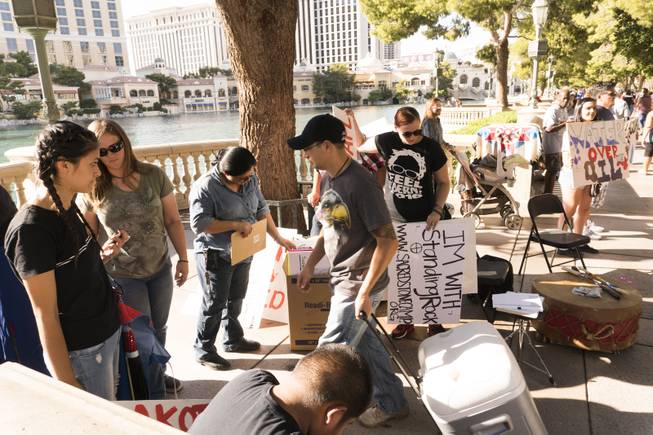 People grab signs from the box to join the "We Stand with Standing Rock" protest in support of the Standing Rock Sioux tribe, in front of the Bellagio Casino, Friday, Sept. 9, 2016. The Standing Rock Sioux tribe is fighting to stop the Dakota Access Pipeline (DAPL) from passing through their lands in North Dakota, which they say will contaminate the water and violate sacred grounds.