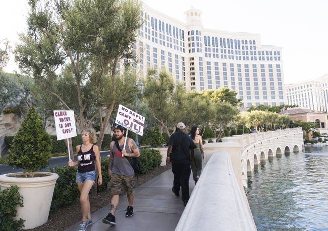 Two protestors with signs make their way to join the "We Stand with Standing Rock" protest in support of the Standing Rock Sioux tribe, in front of the Bellagio Casino, Friday, Sept. 9, 2016. The Standing Rock Sioux tribe is fighting to stop the Dakota Access Pipeline (DAPL) from passing through their lands in North Dakota, which they say will contaminate the water and violate sacred grounds.
