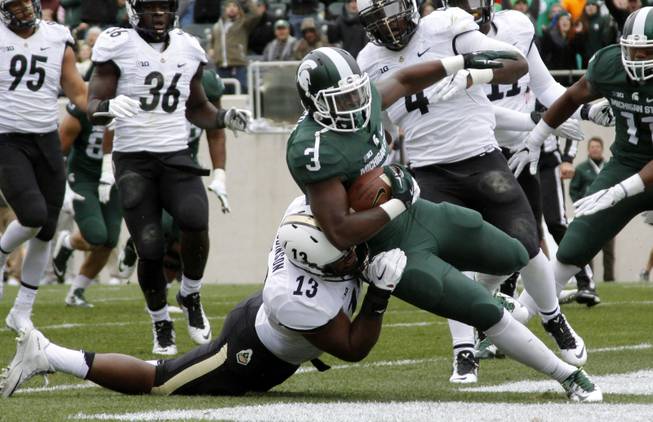 Michigan State's L.J. Scott (3) scores a first-quarter touchdown against Purdue's Gelen Robinson (13) and Ja'Whaun Bentley (4) during an NCAA college football game, Saturday, Oct. 3, 2015, in East Lansing, Mich. 