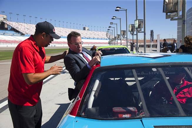 Tino Garcia, left, track operations manager for the Richard Petty Driving Experience, assists Paul Schneider, Nevada Division assistant administrator for the Federal Highway Administration, into a NASCAR-style race car during a Nevada Department of Transportation (NDOT) news conference at the Las Vegas Motor Speedway Monday, Sept. 19, 2016. NDOT announced the groundbreaking of a $33.8 million widening of I-15 between Craig Road and the Speedway.