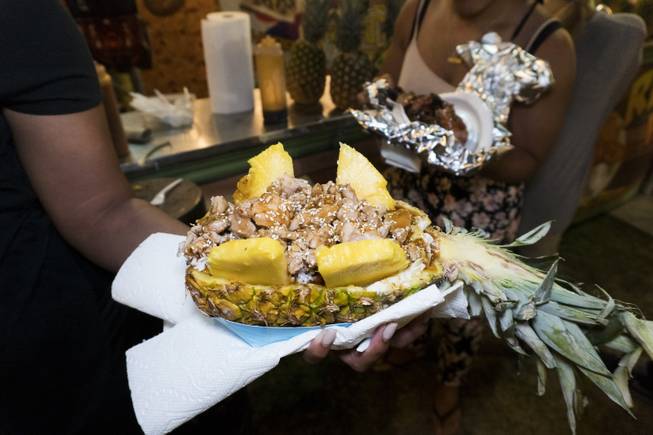 A festival goer holds out a chicken dish served in a pineapple to take a photo of it during the 37th Annual San Gennaro Feast Festival at Craig Ranch Park in North Las Vegas, Friday, Sept. 16, 2016.