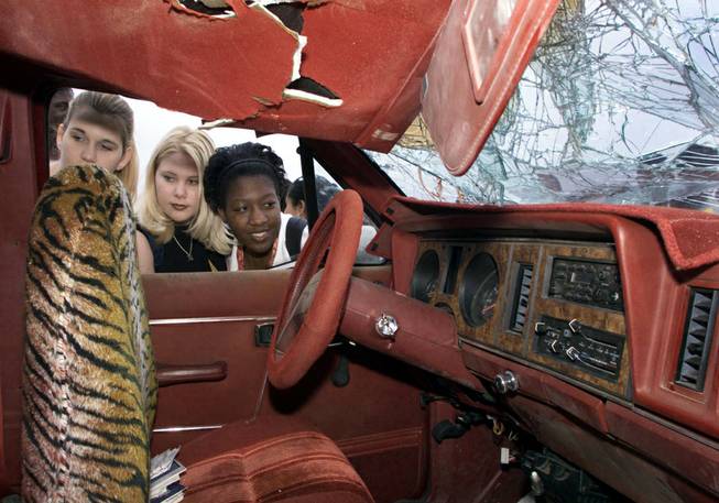 In this file photo, Amy Brinkerhoff, left, Sheila Nessinger, center, and Jackie Patterson, Clark High School seniors look over a wrecked sports utility vehicle at the school Monday, May 24, 1999. The vehicle rolled in an accident last Thursday critically injuring a 16-year-old driver and a passenger who were ejected from the vehicle, said Mike Bernstein, a member of the Safe Communities Coalition. The Coalition brought the vehicle as well as other exhibits as a kick-off to the "Get It On" Buckle Up Campaign. 