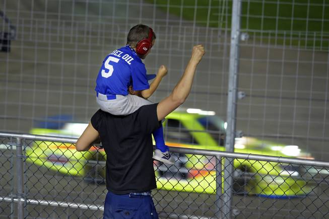 Jeff Schneider III sits on his father Jeff Schneider Jr.'s shoulders as they cheer on their driver during the NASCAR Camping World Truck Series - DC Solar 350 race at the Las Vegas Motor Speedway Saturday, Oct. 1, 2016.