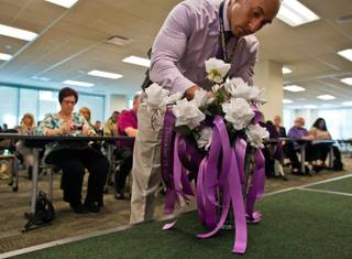 Another rose is added to a vase as victims who lost their lives due to domestic violence are remembered at a ceremony hosted by the Las Vegas Metropolitan Police Department and the Community Coalition for Victims' Rights on Thursday, Oct. 6, 2016.