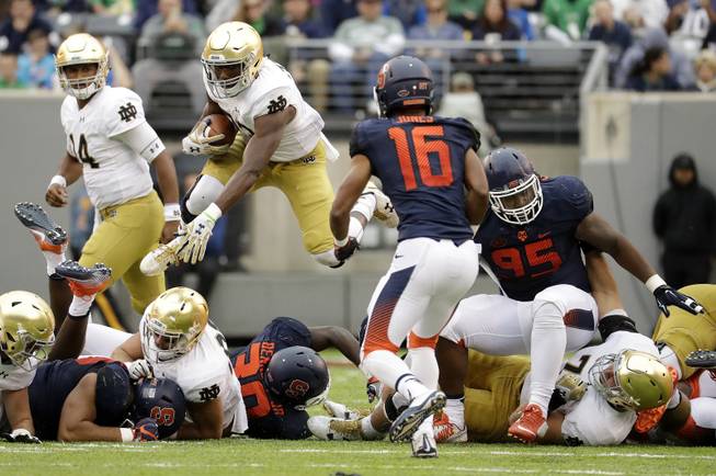 Notre Dame running back Josh Adams leaps over players while rushing for yardage during the second half of an NCAA college football game against Syracuse, Saturday, Oct. 1, 2016, at MetLife Stadium in East Rutherford, N.J. Notre Dame won 50-33. 