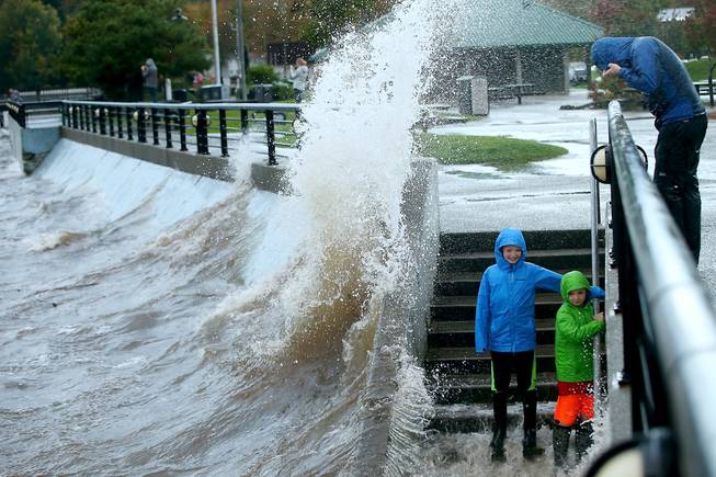 As a wave crashes into the wall, from left, Maxwell Gendreau, 12, his brother Cameron, 11, and his father Eric all brace for a soaking from the spray Saturday, Oct. 15, 2016, as a storm moves in at Silverdale Waterfront Park in Silverdale, Wash.