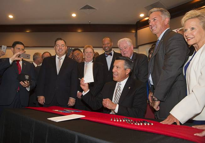 Nevada Governor Brian Sandoval holds up Assembly Bill 1 during a bill signing ceremony at UNLV Monday, Oct. 17, 2016. Sheriff Joe Lombardo stands to the right of Sandoval. The bill authorizes the Clark County Commission to raise the county sales tax by one-tenth of a percentage point to fund more than 300 additional police officers.