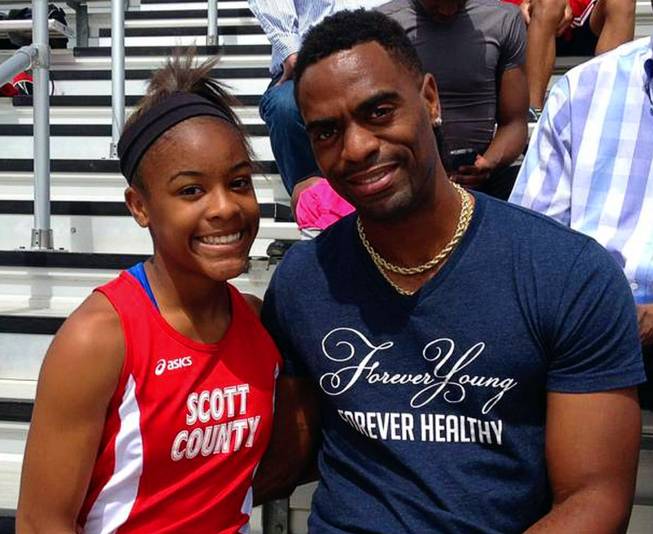In this May 3, 2014, photo, Trinity Gay, a seventh-grader racing for her Scott County High School team, poses for a photo with her father Tyson Gay, after she won the 100 meters and was part of the winning 4-by-100 and 4-by-200 relays at the meet in Georgetown, Ky. The 15-year-old daughter of Olympic sprinter Tyson Gay was fatally shot in the neck, authorities and the athlete's agent said Sunday, Oct. 16, 2016, and police have arrested a man in connection with the shooting. 