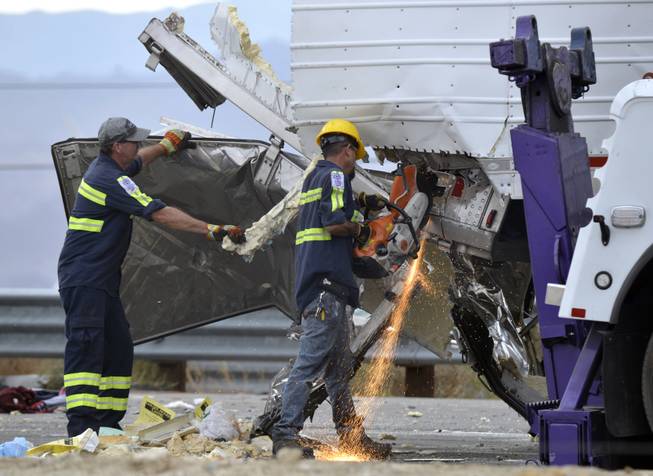 Workers remove wreckage from a semi-truck that crashed with a tour bus on Interstate 10, west of the Indian Canyon Drive off-ramp, in Desert Hot Springs, near Palm Springs, Calif., Sunday, Oct. 23, 2016. A tour bus and the semi-truck crashed on the highway in Southern California early Sunday, killing at least a dozen of people and injuring at least 30 others, some critically, the California Highway Patrol said.