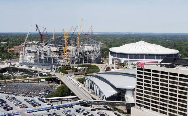 In this May 16, 2016, file photo, Mercedes-Benz Stadium, the future home of the Atlanta Falcons football team stands under construction, at left, next to the team's current stadium, the Georgia Dome, in Atlanta. The 2019 Super Bowl is scheduled to be played at the new stadium.