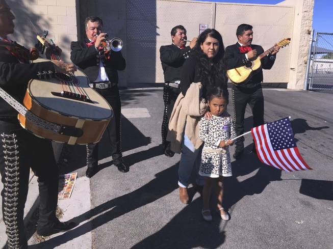 Jacqueline Lima, 20, walks with her four-year-old sister, Karla, holding an American flag, and gets serenaded by a mariachi group after Lima voted for the first time, Tuesday, Nov. 8, 2016, in Las Vegas. Immigrant advocates in Las Vegas worked to get more U.S.-born Latinos to the polls on Election Day as early voter numbers suggest a surge in Hispanic voters. Lima voted for Democrat Hillary Clinton. 