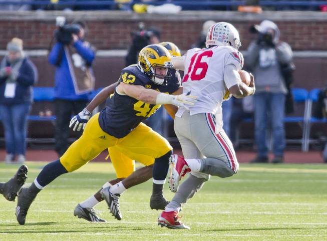 Michigan linebacker Ben Gedeon (42) pressures Ohio State quarterback J.T. Barrett (16) in the fourth quarter of an NCAA college football game in Ann Arbor, Mich., Saturday, Nov. 28, 2015. Ohio State won 42-13. 