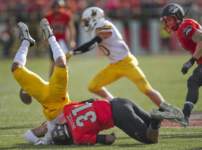 Wyoming's D.J. May (7) is upended and loses the ball after a big shot from UNLVs Salah Boyce (31) causing a turnover and score soon after at Sam Boyd Stadium. 