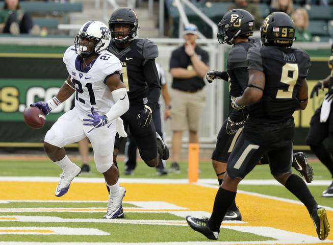 TCU running back Kyle Hicks (21) scores a touchdown on a running play after getting past Baylor cornerback Jameson Houston, rear, and cornerback Ryan Reid (9) in the first half of an NCAA college football game, Saturday, Nov. 5, 2016, in Waco, Texas. 
