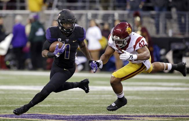 Washington's John Ross, left, runs with the ball as Southern California's Uchenna Nwosu chases him in the first half of an NCAA college football game Saturday, Nov. 12, 2016, in Seattle. 