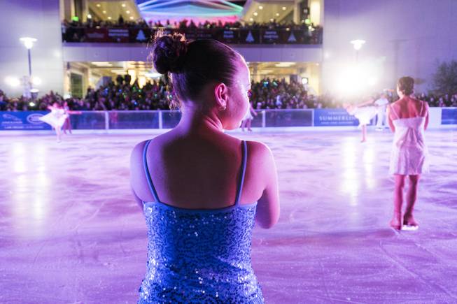 An ice skater looks on as other ice skaters perform during the Downtown Summerlin Holiday Parade which included the tree lighting celebration, Friday, Nov. 18, 2016.