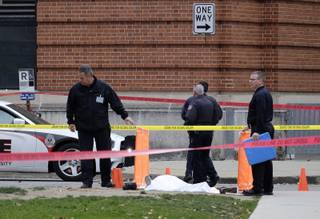 Police cover the body of a suspect outside Watts Hall on the campus of Ohio State University in Columbus, Ohio, following an attack on campus that left several people injured on Monday, Nov. 28, 2016. The man, identified as Abdul Razak Ali Artan, plowed his car into a group of pedestrians and began stabbing people with a butcher knife Monday before he was shot to death by a police officer.  (Adam Cairns/The Columbus Dispatch via AP)