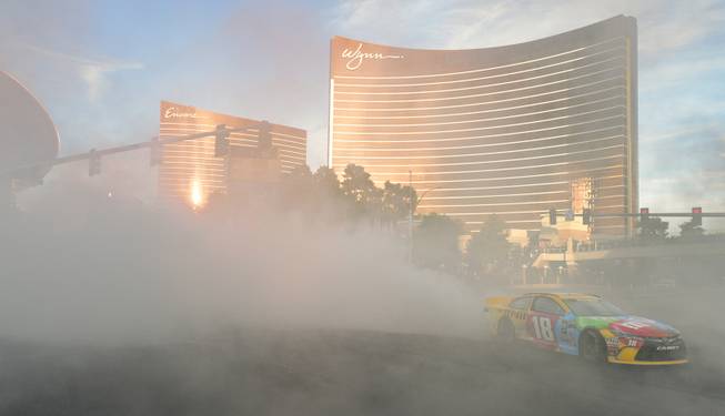 NASCAR's Kyle Busch emerges from a cloud of smoke in his No. 18 Toyota Camry for Joe Gibbs Racing in NASCAR Champions Week Victory Lap on the Las Vegas Strip at the intersection of Spring Mountain Road on Thursday, Dec. 1, 2016.