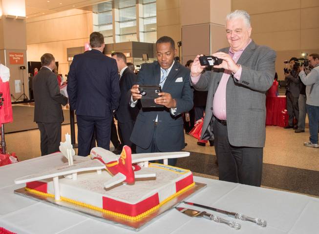 Clark County Commissioners Lawrence Weekly, left, and Steve Sisloak grab a photo of a special cake which celebrates the arrival of Hainan Airlines first flight from Beijing to McCarran International Airport in Las Vegas on Friday, Dec. 2, 2016.