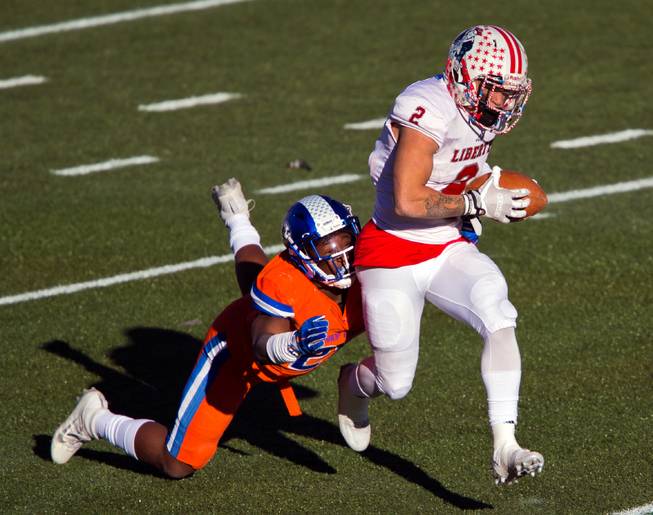 Liberty's Ethan Dedeaux (2) drives out of a tack attempt by Bishop Gorman's Sinjin Torres (21) during their high school football state championship game at Sam Boyd Stadium on Saturday, Dec. 3, 2016.