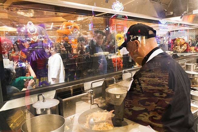 Performers from the Lohan School of Shaolin are seen in the background performing as a cook at Dragons Alley prepares fresh Chinese cuisine during Lucky Dragons grand opening celebration, Saturday, Dec. 3, 2016.