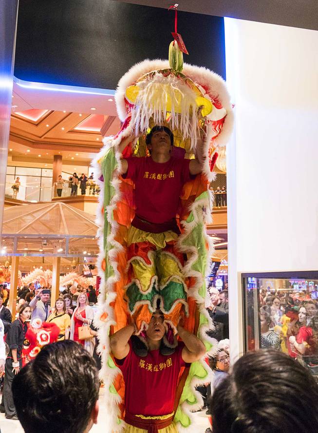Performers from the Lohan School of Shaolin reach for lettuce or chin (a symbol of wealth and luck) during a traditional lion dance during Lucky Dragons grand opening celebration, Saturday, Dec. 3, 2016.