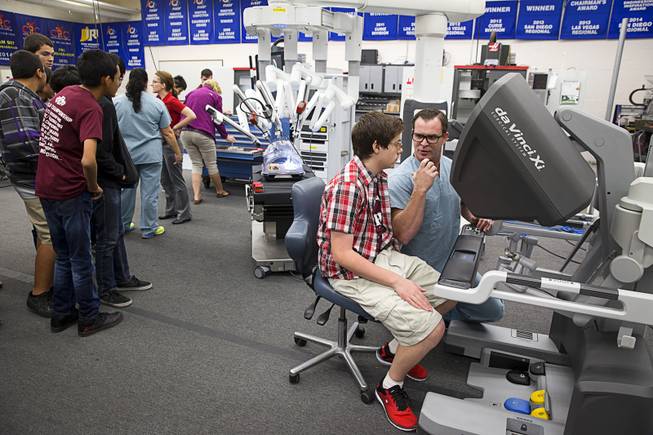 Chance Larsen, a senior clinical sales representative at Intuitive Surgical, gives advice to Jordan Wiseman as he tries out Intuitive's da Vinci Xi robotic surgical system at the Cimarron-Memorial High School engineering lab Tuesday, Dec. 6, 2016. MountainView Hospital and Intuitive Surgical, Inc. partnered in the event to teach students about careers in robotics, engineering and medicine.