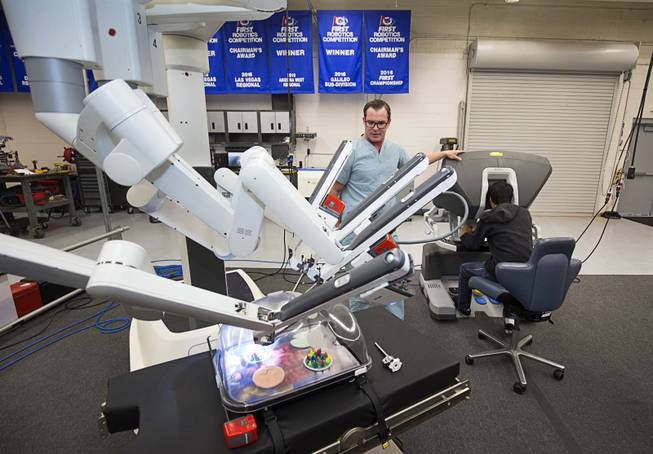Chance Larsen, a senior clinical sales representative at Intuitive Surgical, watches as a student operates Intuitive's da Vinci Xi robotic surgical system at the Cimarron-Memorial High School engineering lab Tuesday, Dec. 6, 2016. MountainView Hospital and Intuitive Surgical, Inc. partnered in the event to teach students about careers in robotics, engineering and medicine.