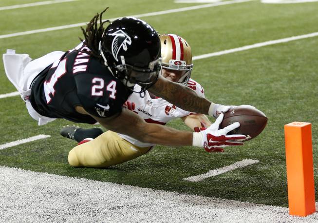 Atlanta Falcons running back Devonta Freeman, left, makes the reach near the goal line past a 49ers defender during the first half of an NFL game Sunday, Dec. 18, 2016, in Atlanta.