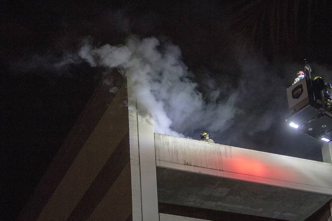 Firefighters fight a car fire located on the top floor of a downtown Las Vegas parking garage, Monday, Feb. 27, 2017.