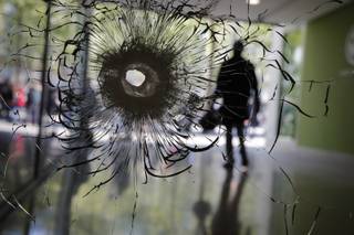 A bullet hole is pictured on a shopwindow of the Champs Elysees boulevard in Paris, Friday, April 21, 2017. France began picking itself up Friday from another deadly shooting claimed by the Islamic State group, with President Francois Hollande convening the government's security council and his would-be successors in the presidential election campaign treading carefully before voting this weekend. (AP Photo/Christophe Ena)
