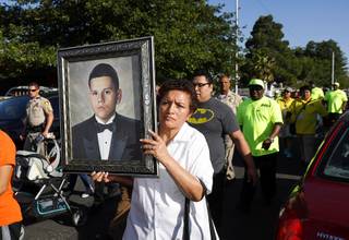 A family friend holds a portrait of slain teen Jose de Jesus Alatorre Guzman during a march and vigil in a neighborhood near Decatur Boulevard and Bonanza Road Monday, May 15, 2017. Alatorre Guzman, 19, was shot and killed in a drive-by shooting on May 11, 2016. The case is yet unsolved.