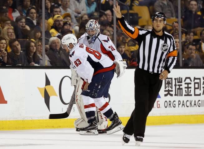 As the referee signals for a four minute penalty against the Boston Bruins, Washington Capitals' Jay Beagle (83) is led to the bench by goalie Philipp Grubauer after being injured during the third period of Washington's 3-1 win in an NHL hockey game in Boston, Saturday, April 8, 2017. 