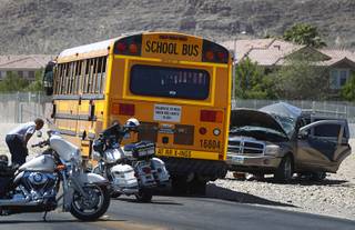 A mechanic, left, looks over a bus after an accident involving a Clark County School District bus and a SUV on Fort Apache Road near Post Road Thursday, May 25, 2017.