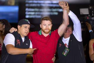 Boxer Canelo Alvarez of Mexico poses with co-trainer Eddy Reynoso, left, and trainer Jose 