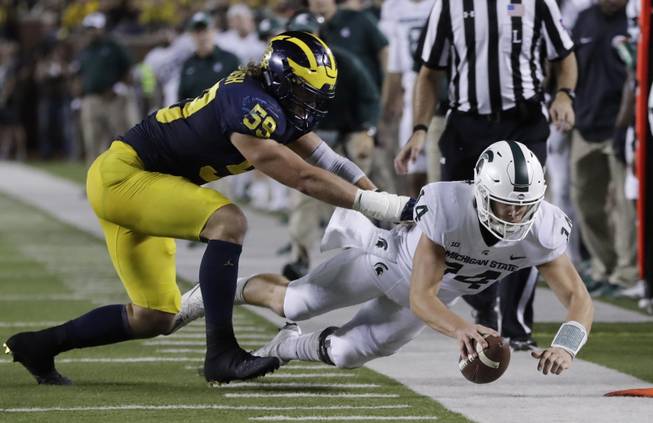 Michigan State quarterback Brian Lewerke (14) stretches for yardage as he is pushed out of bounds by Michigan linebacker Noah Furbush (59) during the first half of an NCAA college football game, Saturday, Oct. 7, 2017, in Ann Arbor, Mich. 