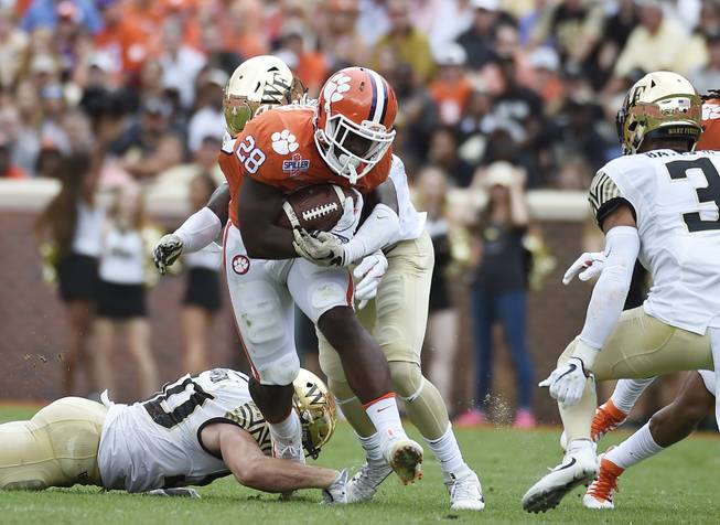 Clemson running back Tavien Feaster (28) runs for yardage against Wake Forest defensive players during the first half of an NCAA college football game, Saturday, Oct. 7, 2017, in Clemson, S.C. (AP Photo/Rainier Ehrhardt)