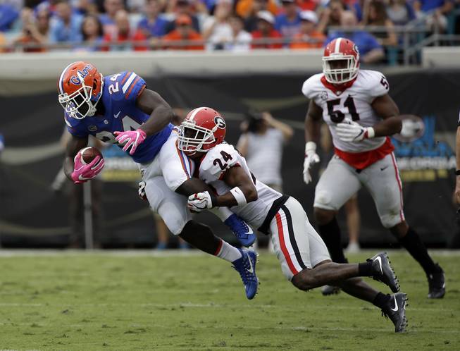 Florida running back Mark Thompson, left, is stopped by Georgia safety Dominick Sanders for a short gain in the first half of an NCAA college football game, Saturday, Oct. 28, 2017, in Jacksonville, Fla. 