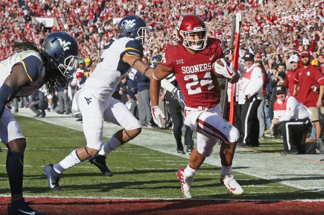 Oklahoma running back Rodney Anderson (24) scores in front of West Virginia safety Kenny Robinson (2) in the first quarter of an NCAA college football game in Norman, Okla., Saturday, Nov. 25, 2017. 