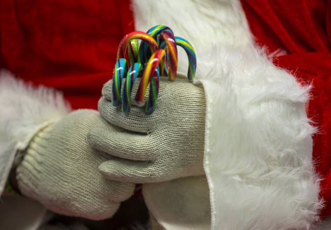 Santa gives out candy canes as Station Casinos and Wildfire Gaming team members distribute holiday gifts to all 600 students at Whitney Elementary School on Wednesday, Dec. 20, 2017.