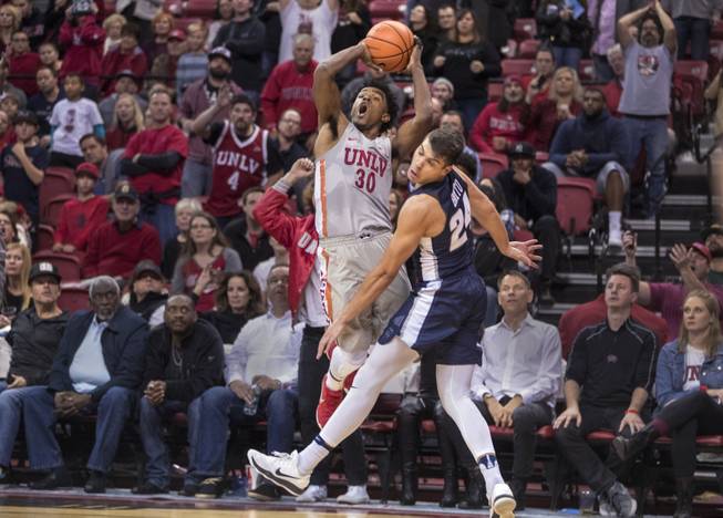 UNLV Rebels guard Jovan Mooring (30) gets off a 3-point shot late while not getting a foul call from Utah State Aggies guard Diogo Brito (24) during their game at the Thomas & Mack Center on Saturday, Jan. 6, 2018.