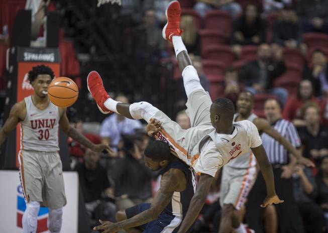 UNLV Rebels forward Cheikh Mbacke Diong (34) topples over Utah State Aggies guard DeAngelo Isby (0) after a pump fake during their game at the Thomas & Mack Center on Saturday, Jan. 6, 2018.